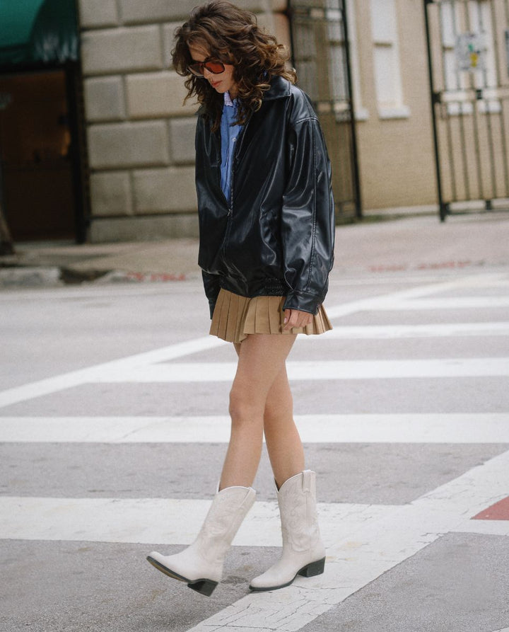 Chica con pelo rizado llevando botas blancas cowboy en la calle