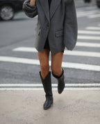 Mujer con traje gris y botas cowboy caña alta negras para mujer