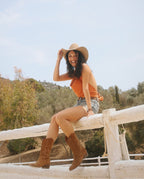 Chica con shorts jeans y botas cowboy en ante marrón media caña