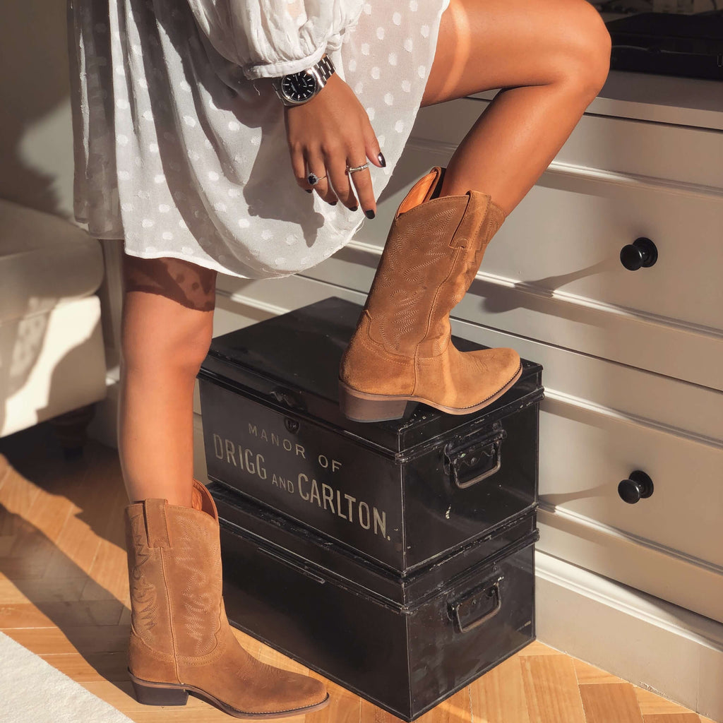 Botas cowboy camel ante mujer con vestido blanco