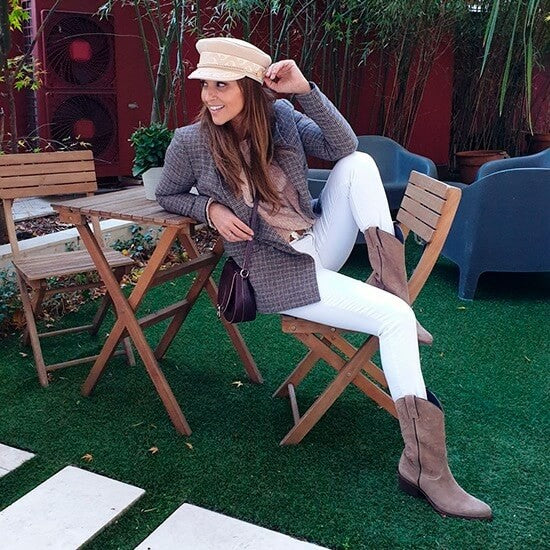 Mujer con jeans blancos, chaqueta gris y botas taupe estilo cowboy